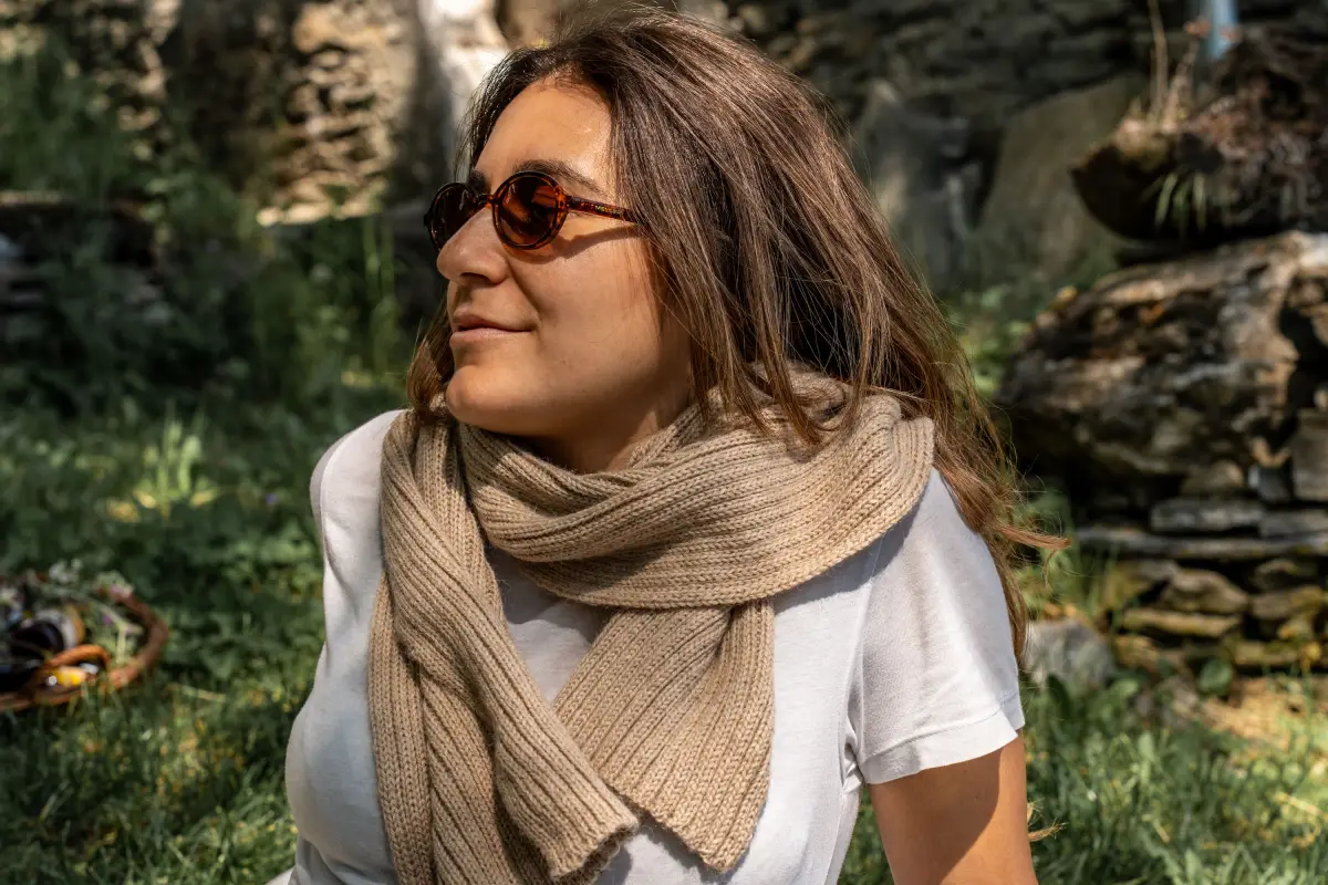 Una sciarpa in lana di alpaca indossata al sole davanti a un muro in pietra