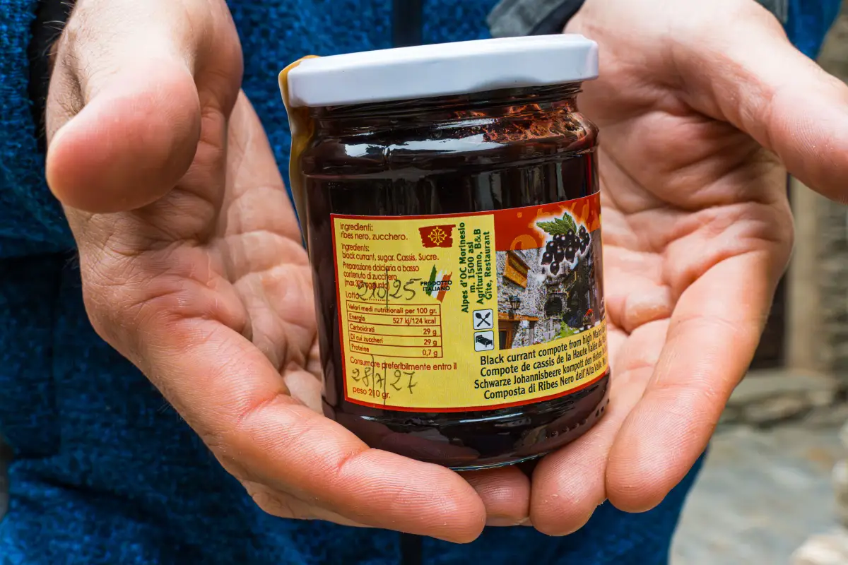 Un vasetto di composta di ribes nero tenuto fra le mani