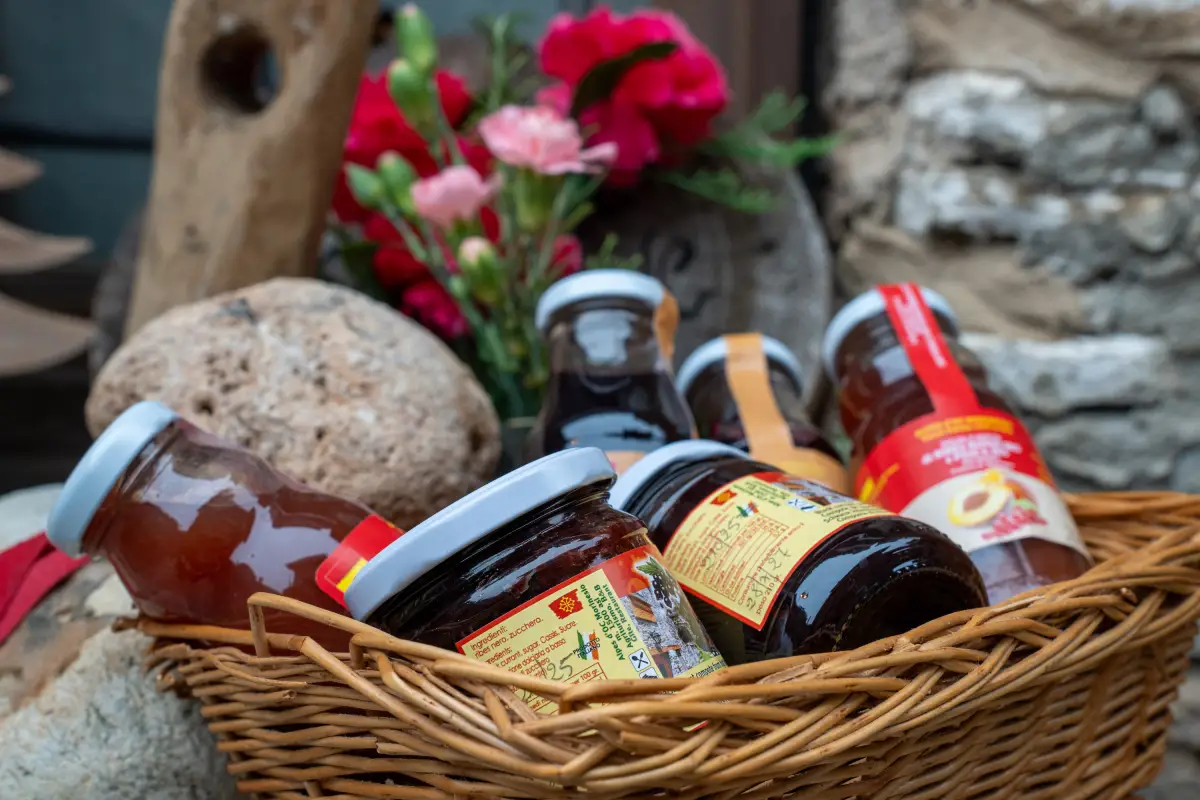 Cesto di composte artigianali con fiori davanti a un muro in pietra